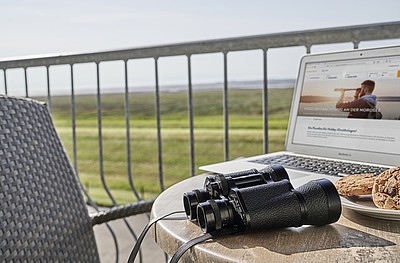 Ausblick aus einer Ferienwohnung in Duhnen vom Balkon. Auf dem Balkon steht ein Laptop un ein Fernglas.